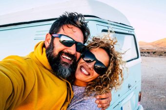 Middle age couple smiling while taking a selfie by their camper